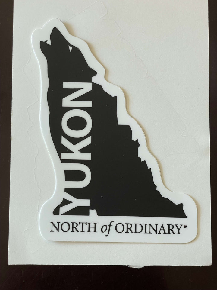 Sticker with wolf silhouette and 'Yukon North of Ordinary' text on a white background