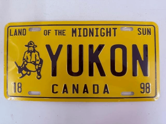 Yellow license plate with black text and graphics, featuring 'Yukon' and 'Canada'.