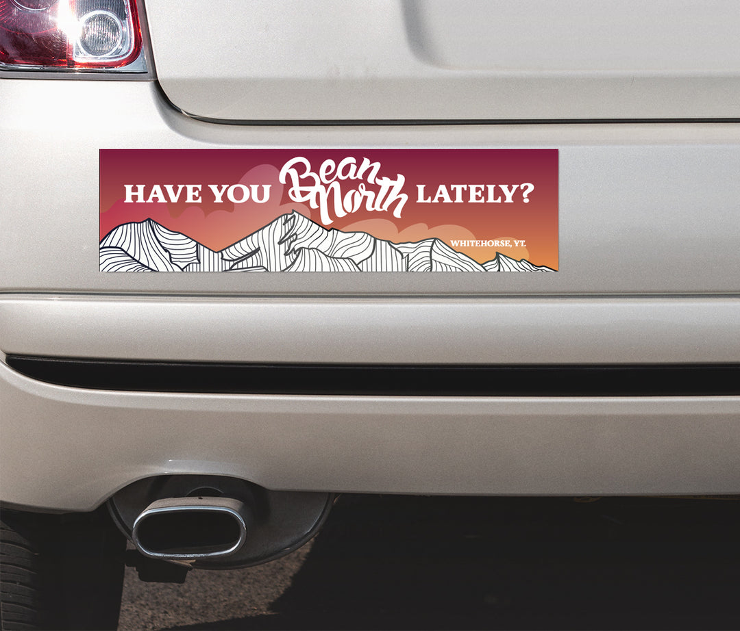 Bumper sticker with mountain design and text on a car
