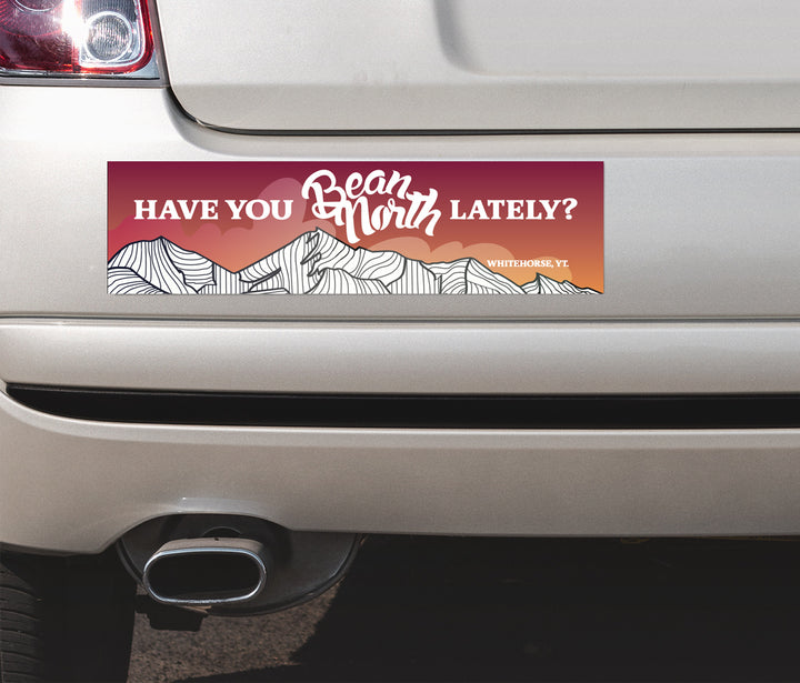 Bumper sticker with mountain design and text on a car
