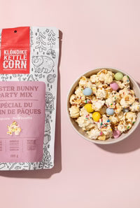 Klondike Kettle Corn Easter Bunny Party Mix packaging with a bowl of popcorn on a pink background
