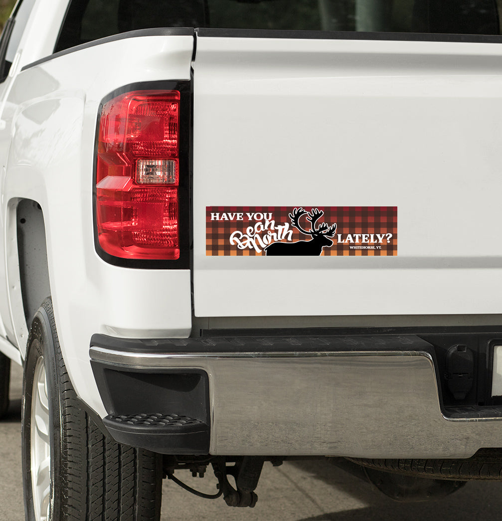 Bumper sticker on a white truck with text and plaid design.
